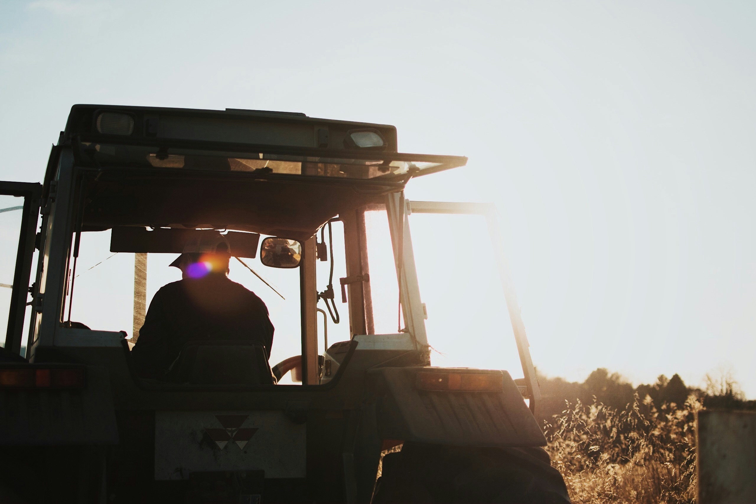 Farmer in a tractor cab at sunset